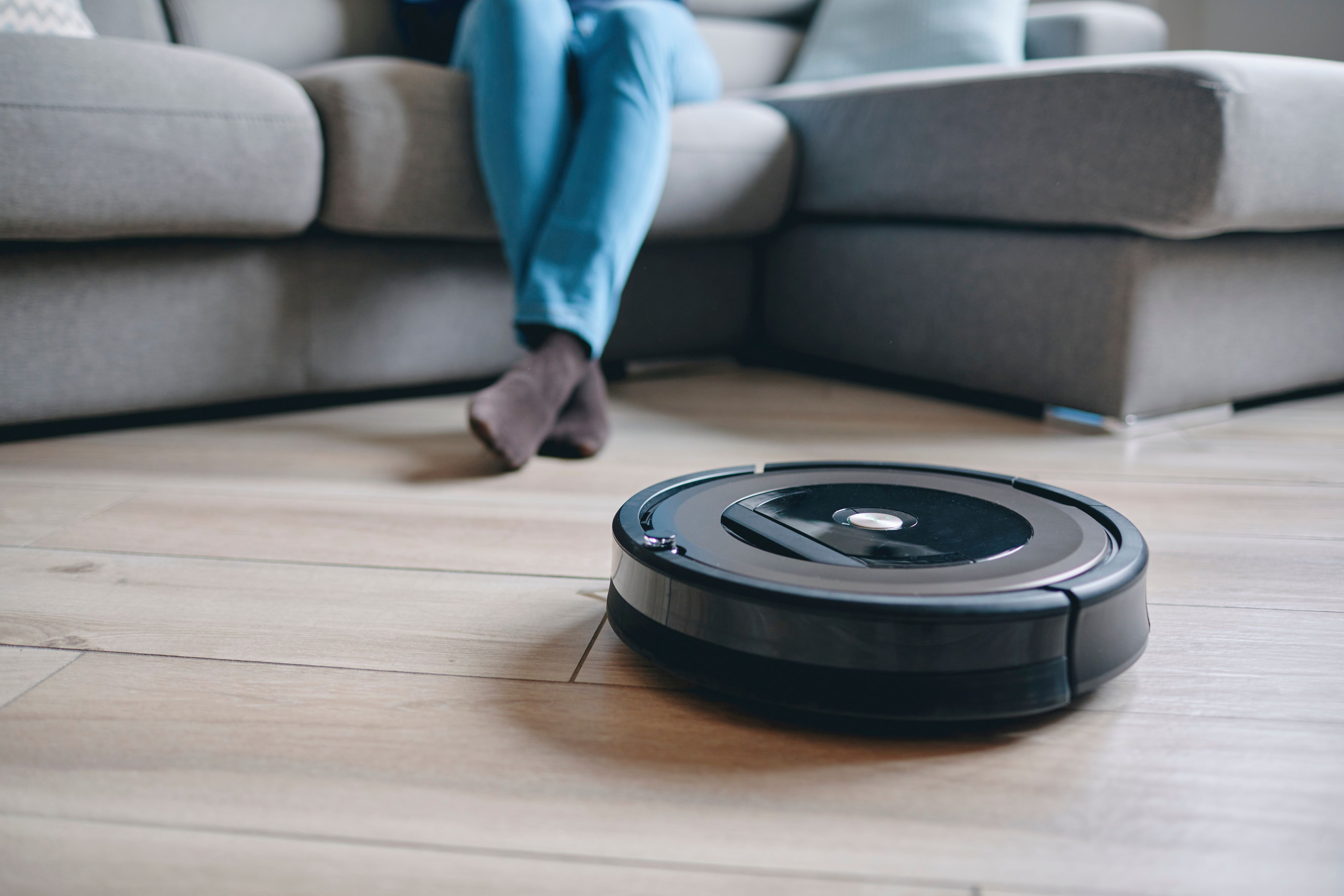 a robot vacuum cleans the floor while a person relaxes