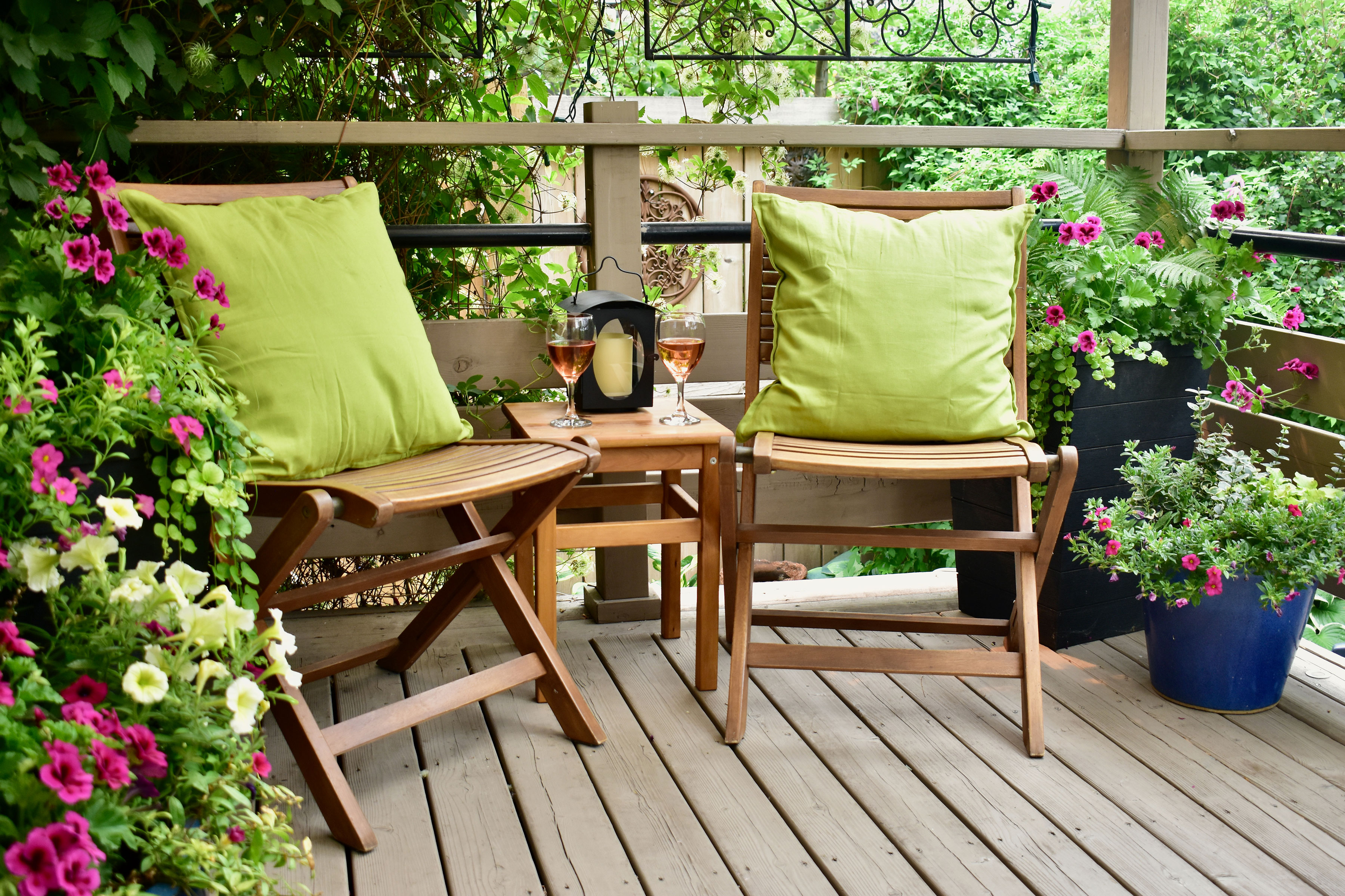 Deck with two chairs and green pillows.