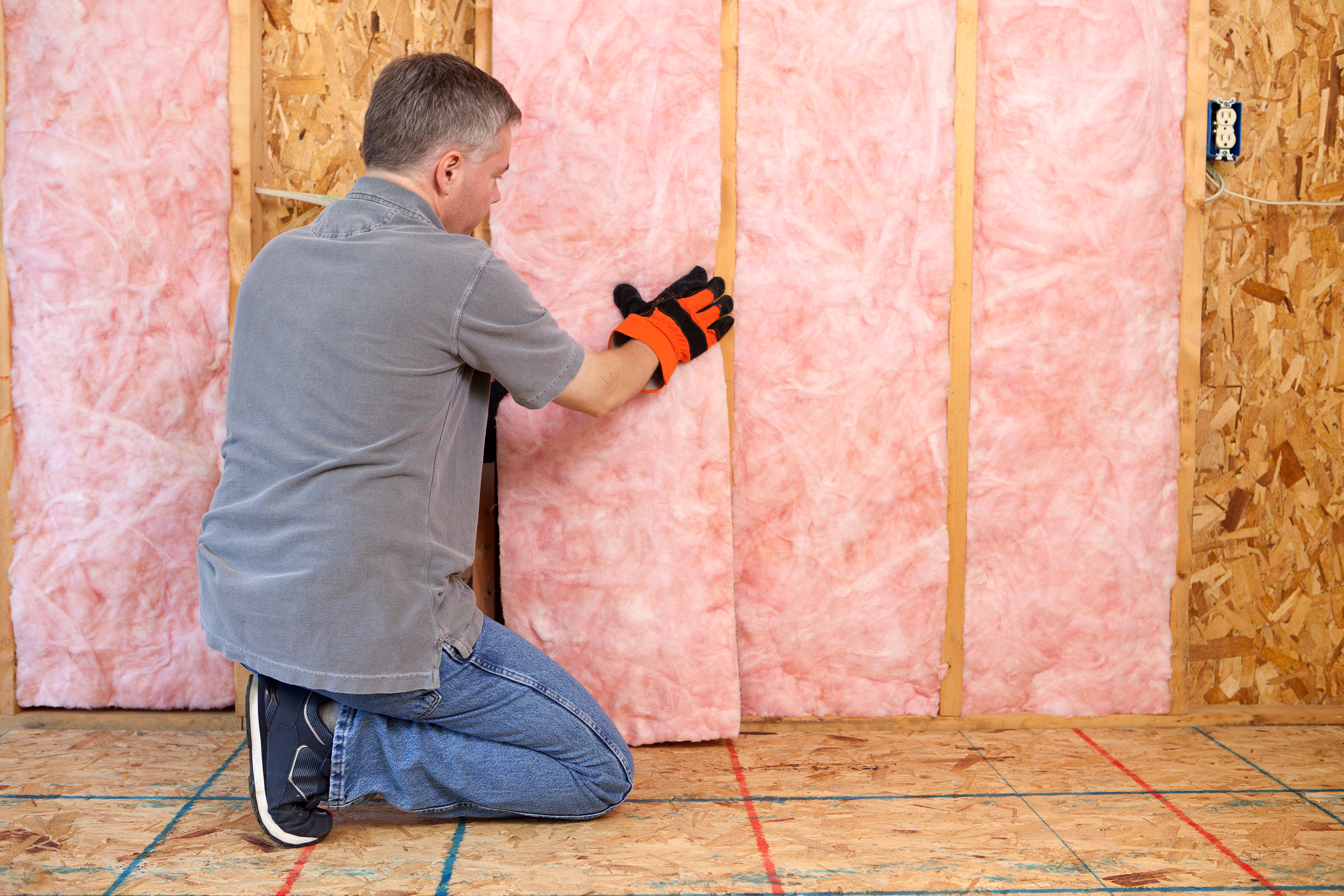 Person installing fiberglass insulation at home