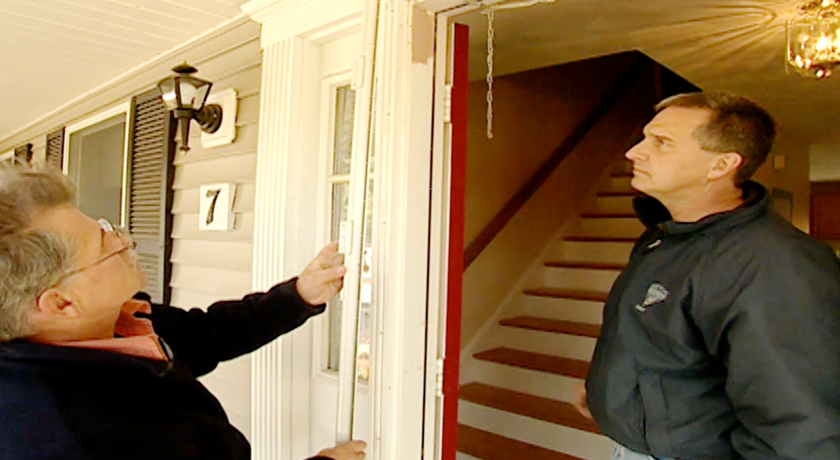 Two people inspect a frosted screen door.